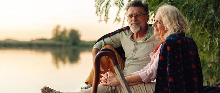 Two people are seated close together near the water's edge