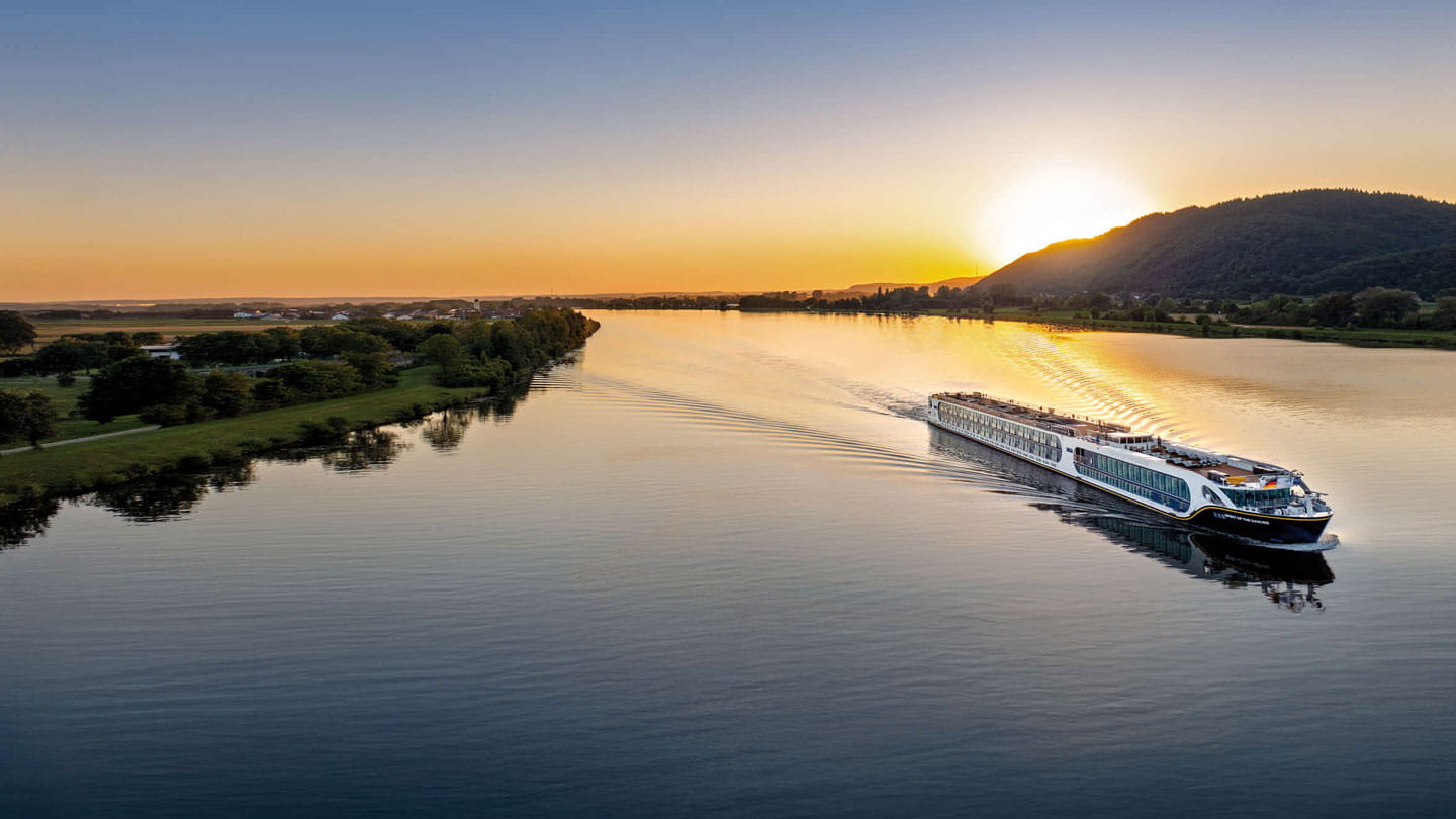 River cruise ship sailing on calm water at sunset