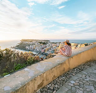 A holidaymaker watching the sunset over a beautiful Greek seaside town