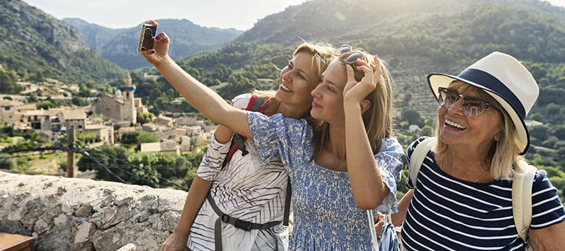A grandmother, mother and daughter taking a selfie on a sunny holiday.