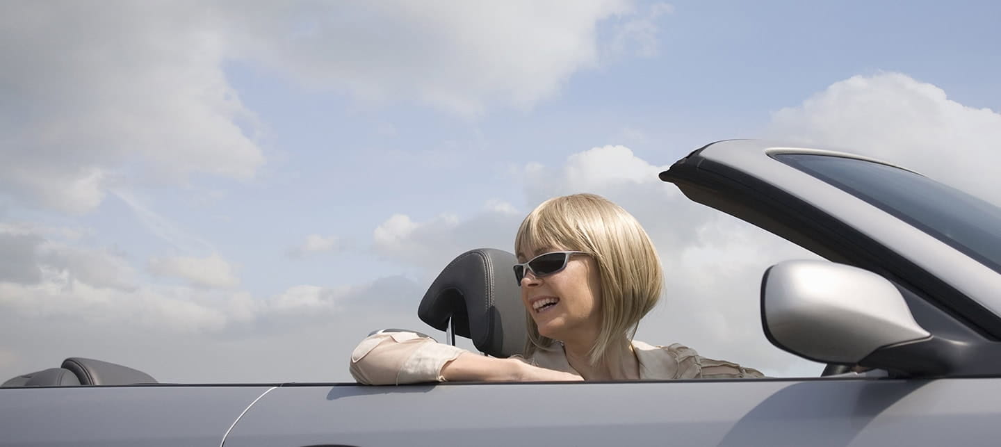 Smiling woman driving a convertible car