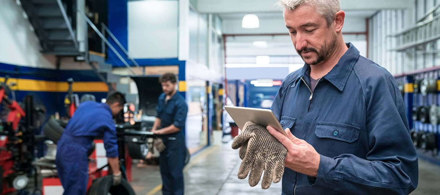 Auto mechanic standing next to the car in a working garage.