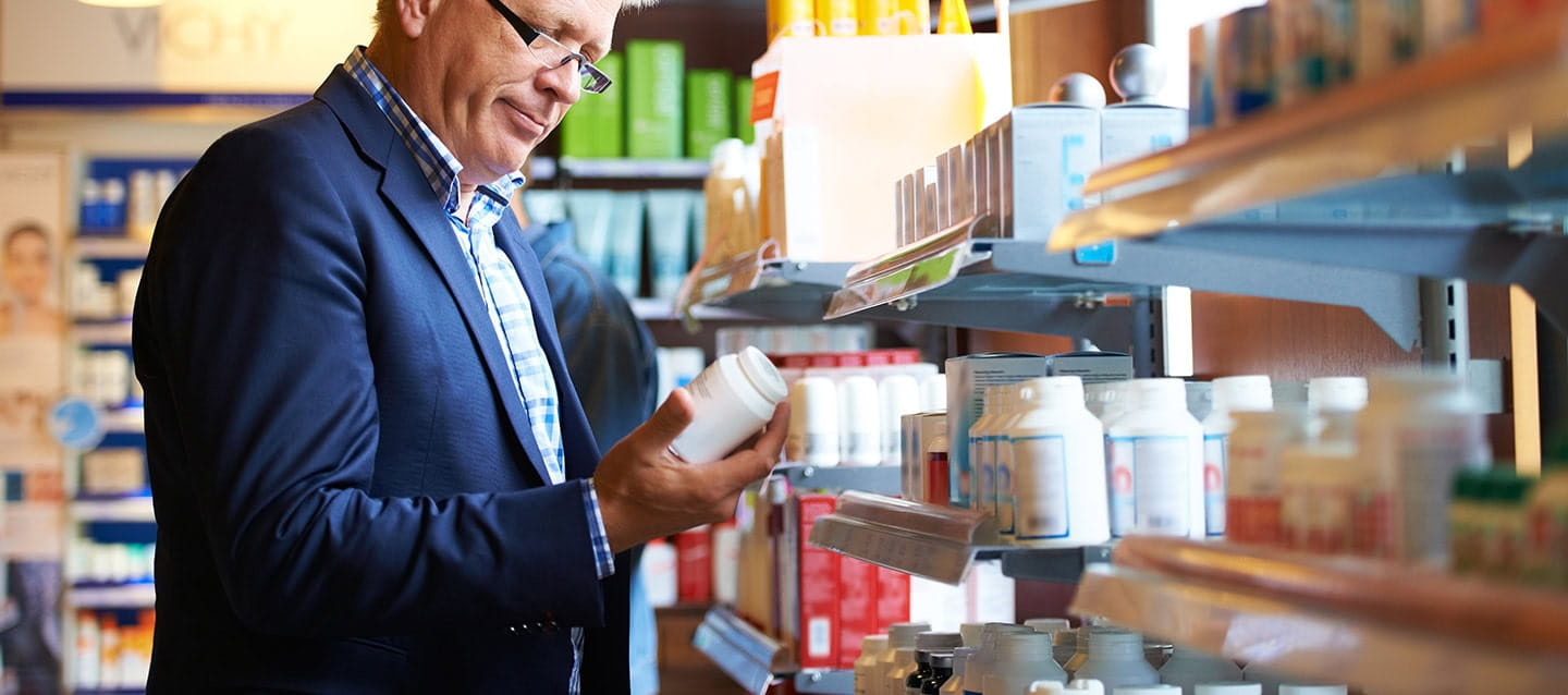 A mature man looking at the vitamin shelf in a chemists.