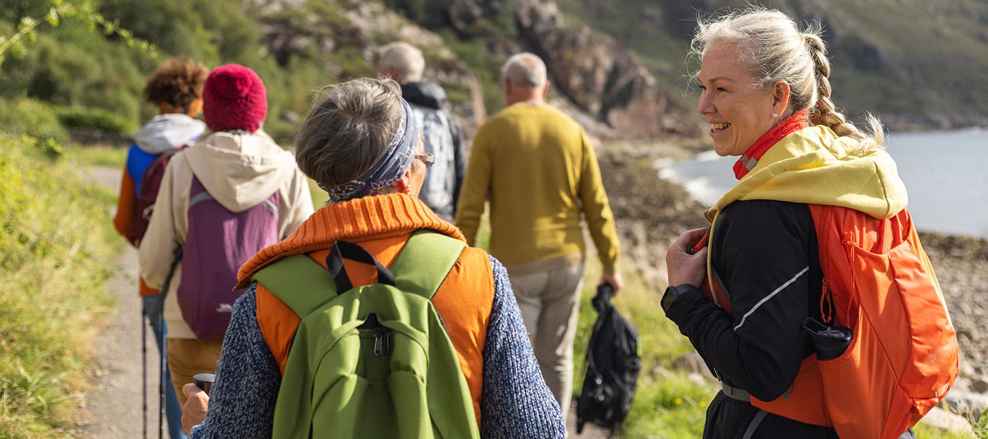 A group of mature and senior friends walking along a footpath near the village of Diabaig on the side of Loch Torridon in the west highlands of Scotland
