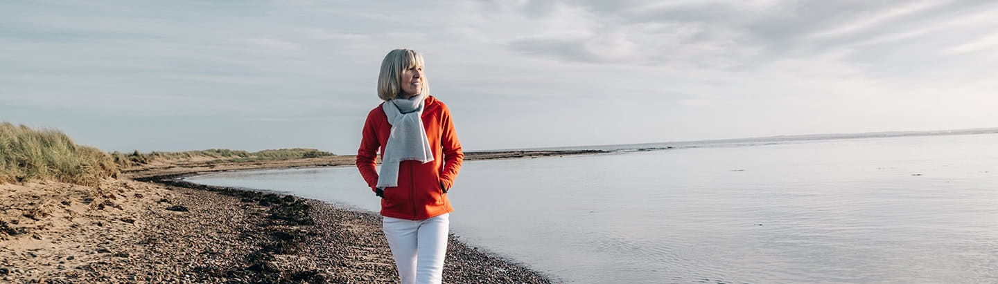 A mature woman enjoying an autumnal walk beside the Loch Fleet Nature Reserve estuary, Sutherland, Scotland