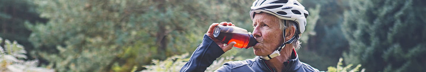 A mature cyclist taking a drinks break in an autumnal forest