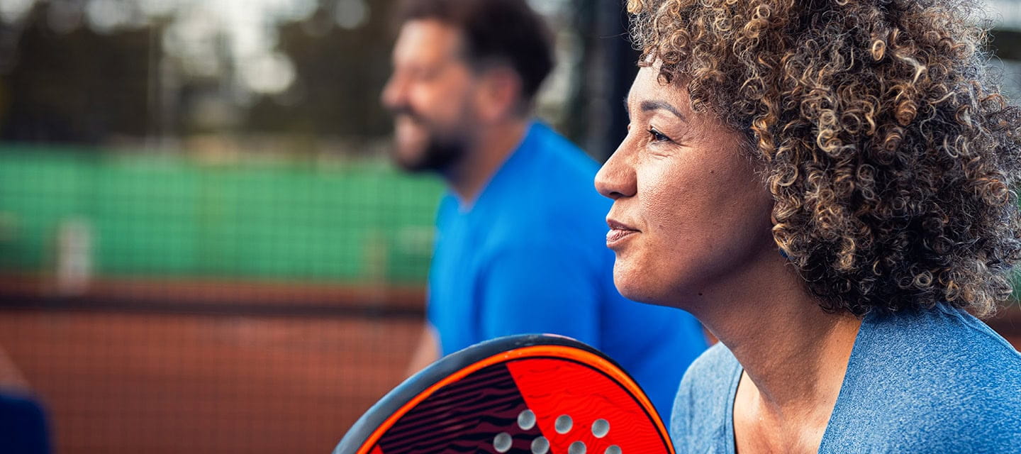 Side view portrait of adult couple playing padel on outdoor court.