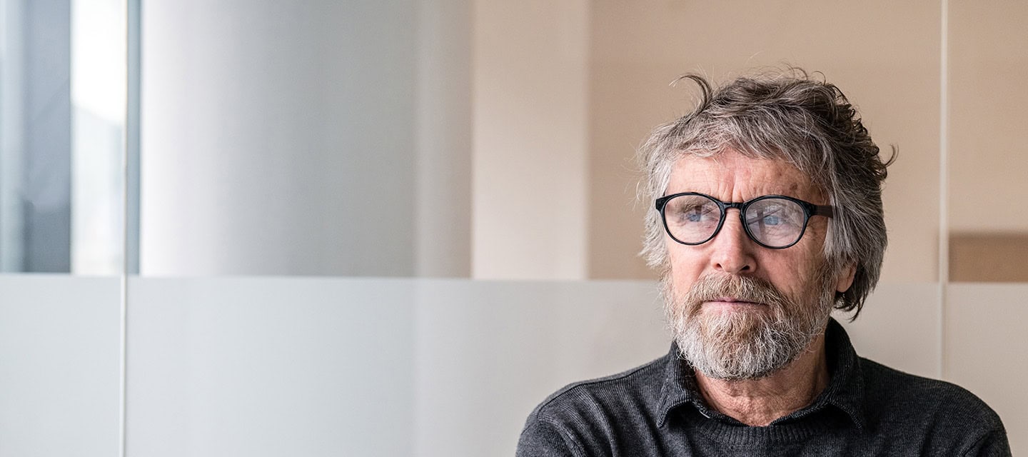 Senior man sat alone wearing glasses.