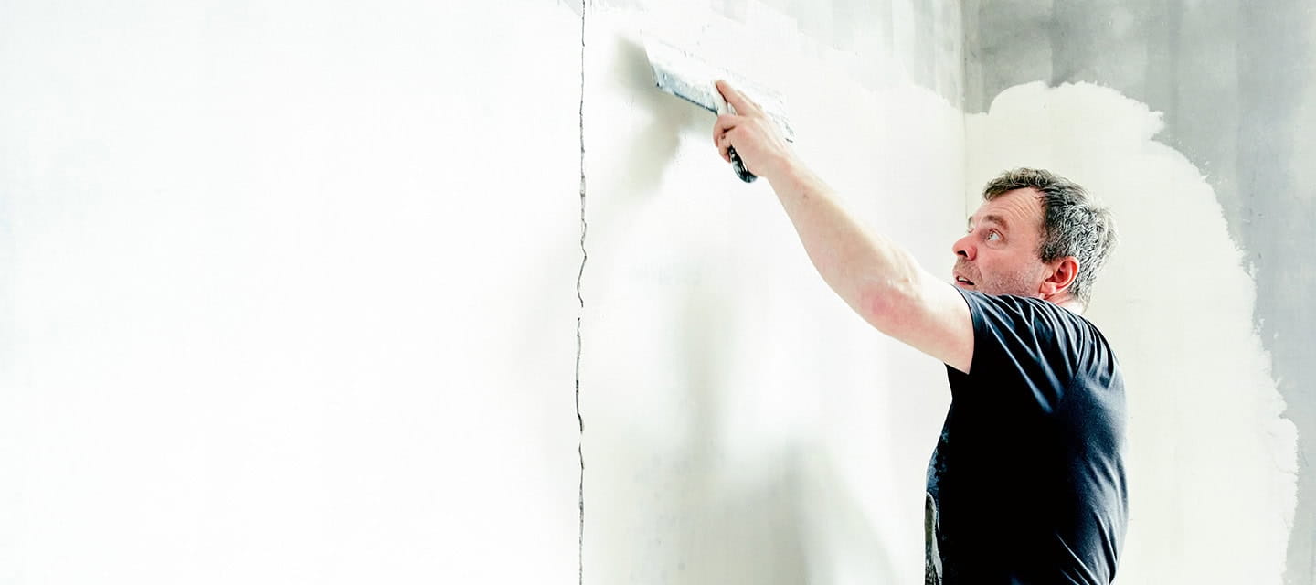 A decorator plastering over a crack in the wall.