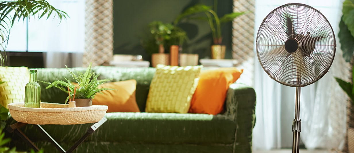 A bright & stylish living room interior and a modern metallic standing fan.