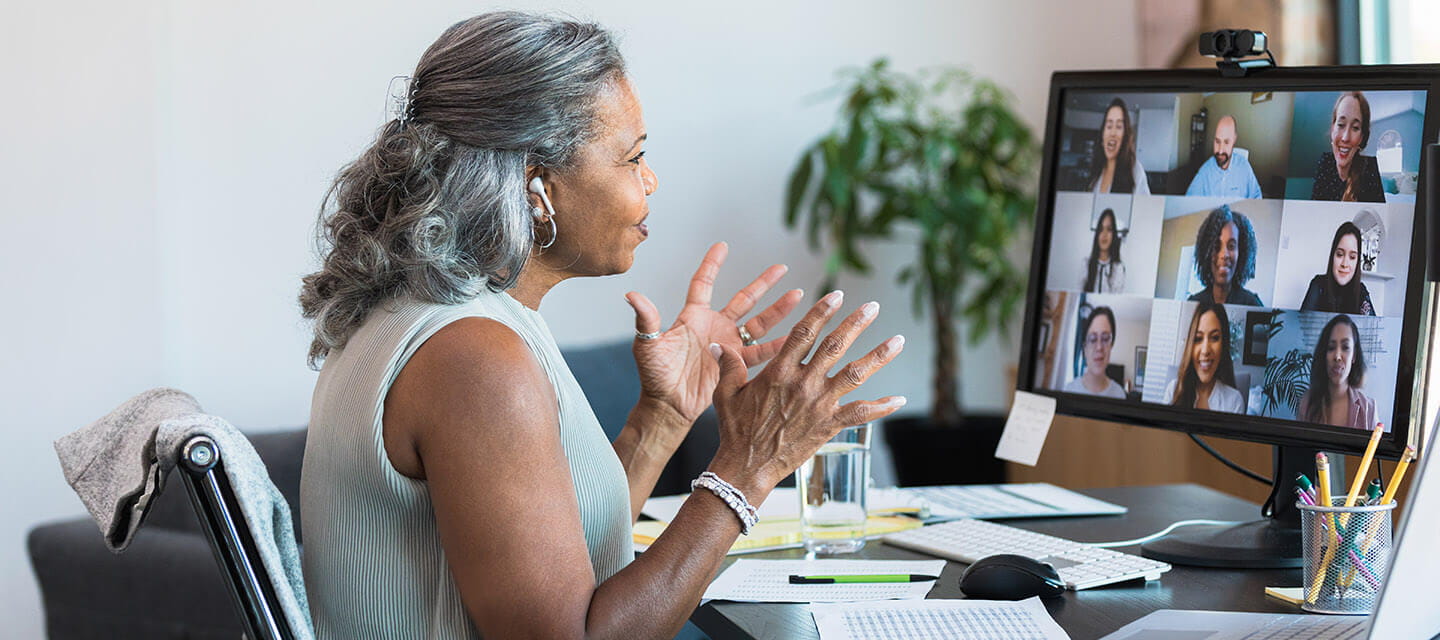 A confident business woman gestures as she presents ideas during a virtual meeting with a group of colleagues.