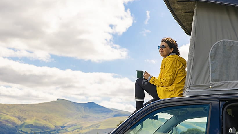 Woman sitting on campervan in the Brecon Beacons