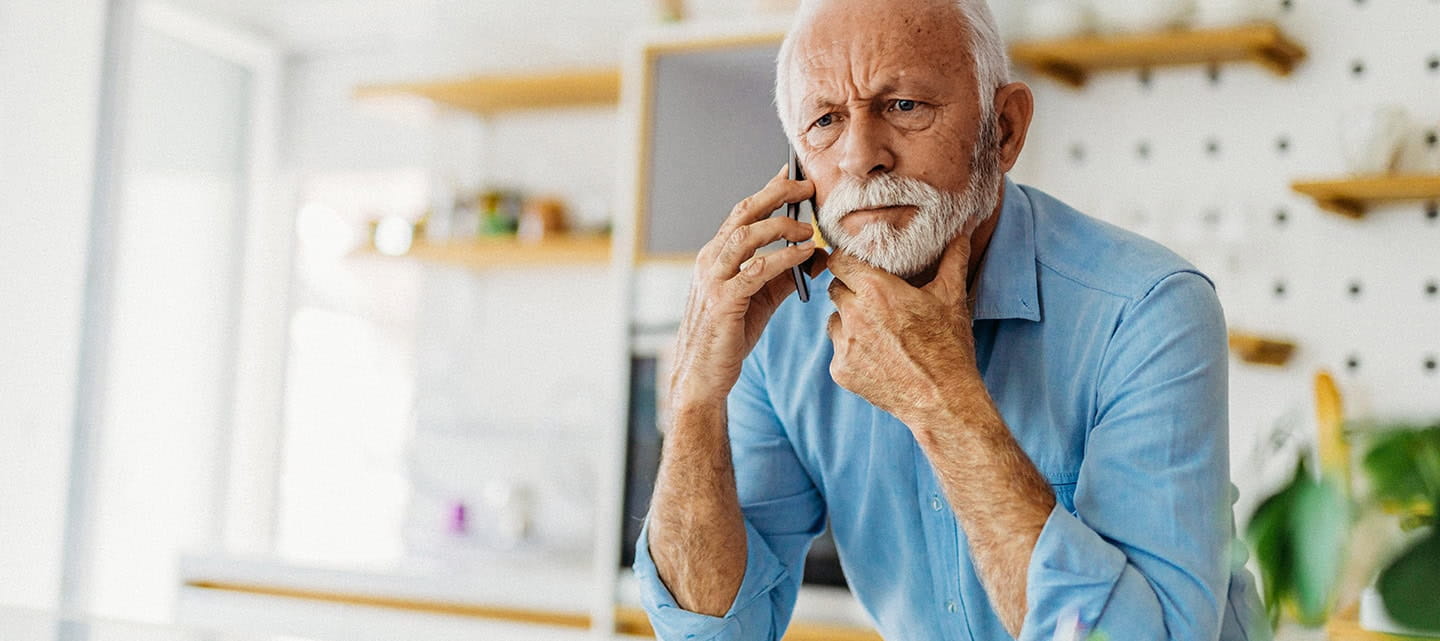 A mature man at home looking concerned while on the phone.