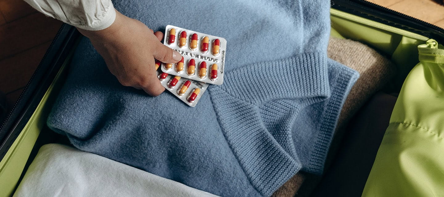 A woman puts her medication in her suitcase, ready for her holiday.