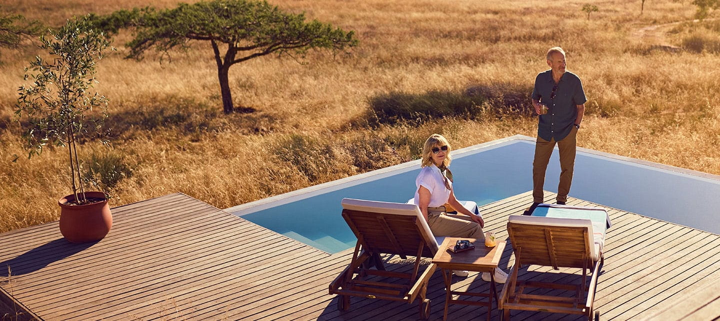 A mature couple relaxing by the pool at a safari retreat in South Africa.