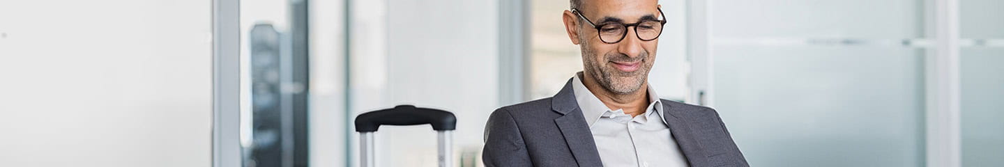 Mature man using mobile phone at the airport in the lounge area.