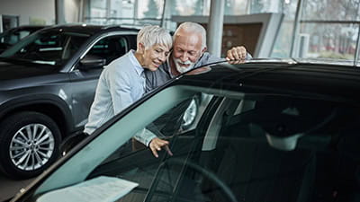 Happy mature couple searching for the right car in a showroom.