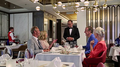 Two mature couples being served dinner on a cruise ship