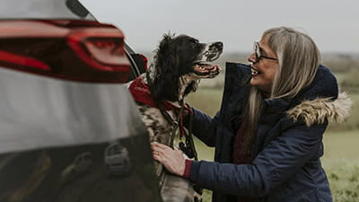 Woman petting her dog at the open boot of her car