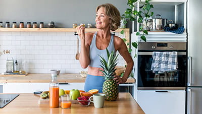 Mature woman at home wearing sportswear eating healthy food after fitness workout