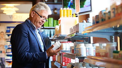 A mature man looking at the vitamin shelf in a chemists.