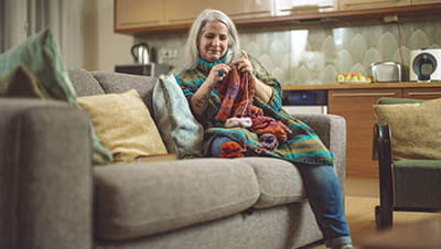 Mature woman is relaxing and knitting at home