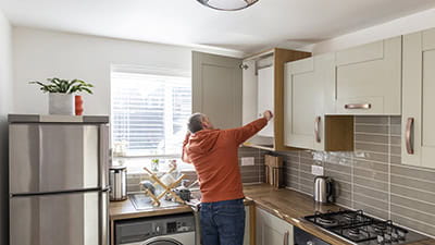 A man in his kitchen adjusting the dials on his combi boiler.