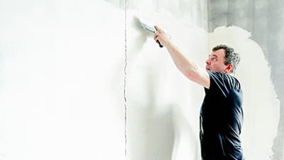 A decorator plastering over a crack in the wall.