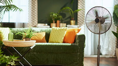 A bright & stylish living room interior and a modern metallic standing fan.