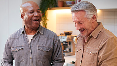 Two middle-aged men sharing a joke in the kitchen