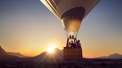 A mature couple enjoying a hot air balloon ride as the sun sets over South Africa.