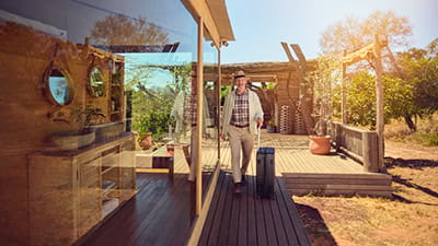 A mature man walks confidently toward a hotel room at a Safari resort in South Africa.