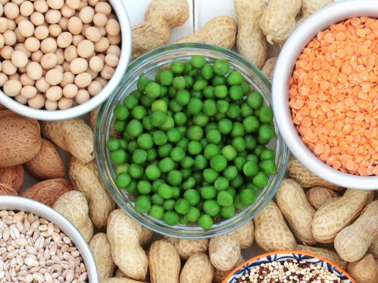 A bowl of peas surrounded by other plant-based foods | Getty/marilyna