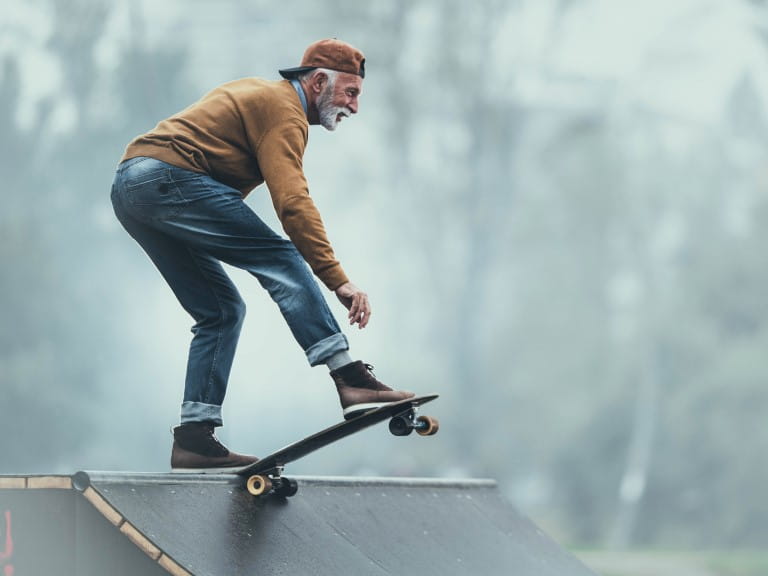 An older man about to skate a skateboard down a ramp | Getty