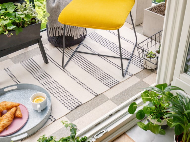 A rug on a balcony beneath a yellow chair