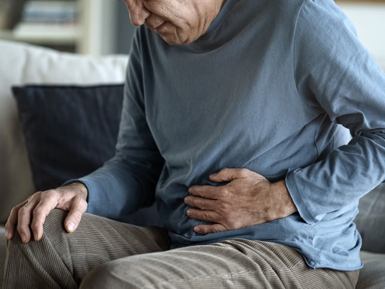 An older man holding his stomach as if in pain