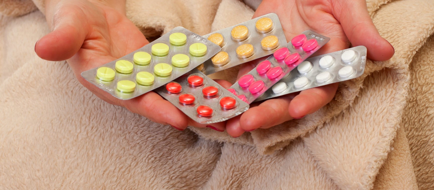 A close up of hands holding several packets of medications to represent statins | Getty/Ocskaymark