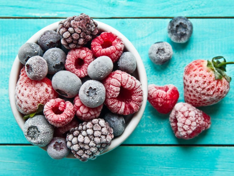 Frozen or frosted berries bowl placed on sea blue wooden background | Getty/sagarmanis