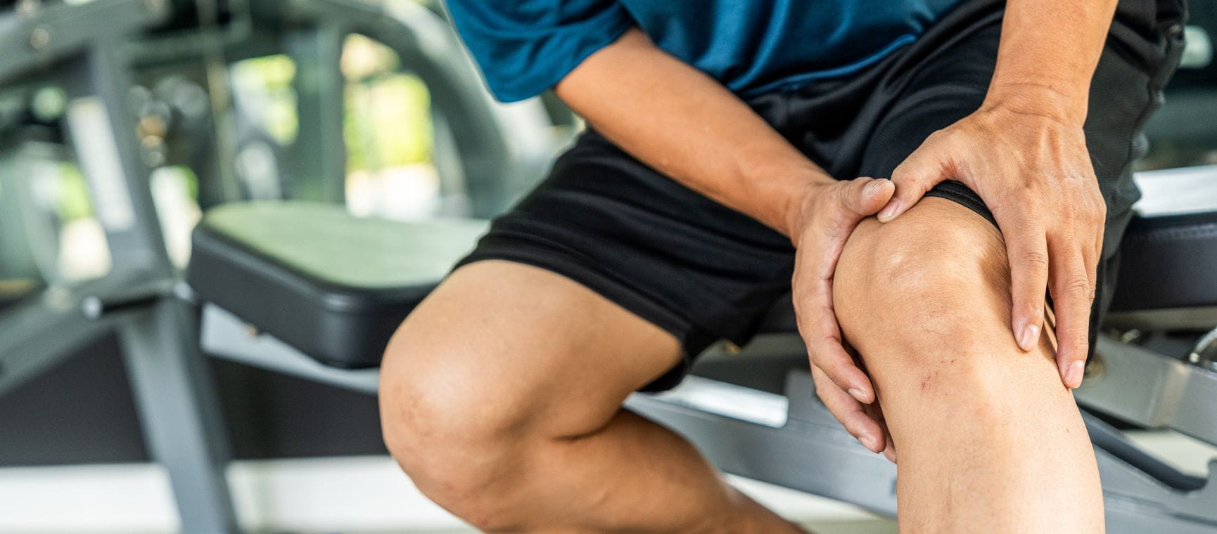 a runner in shorts clutching his knee