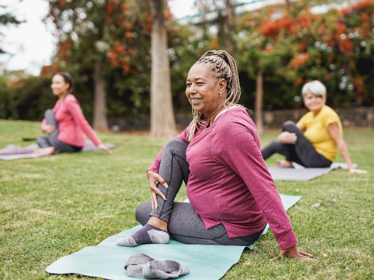 Women in sports attire practising yoga in a park setting