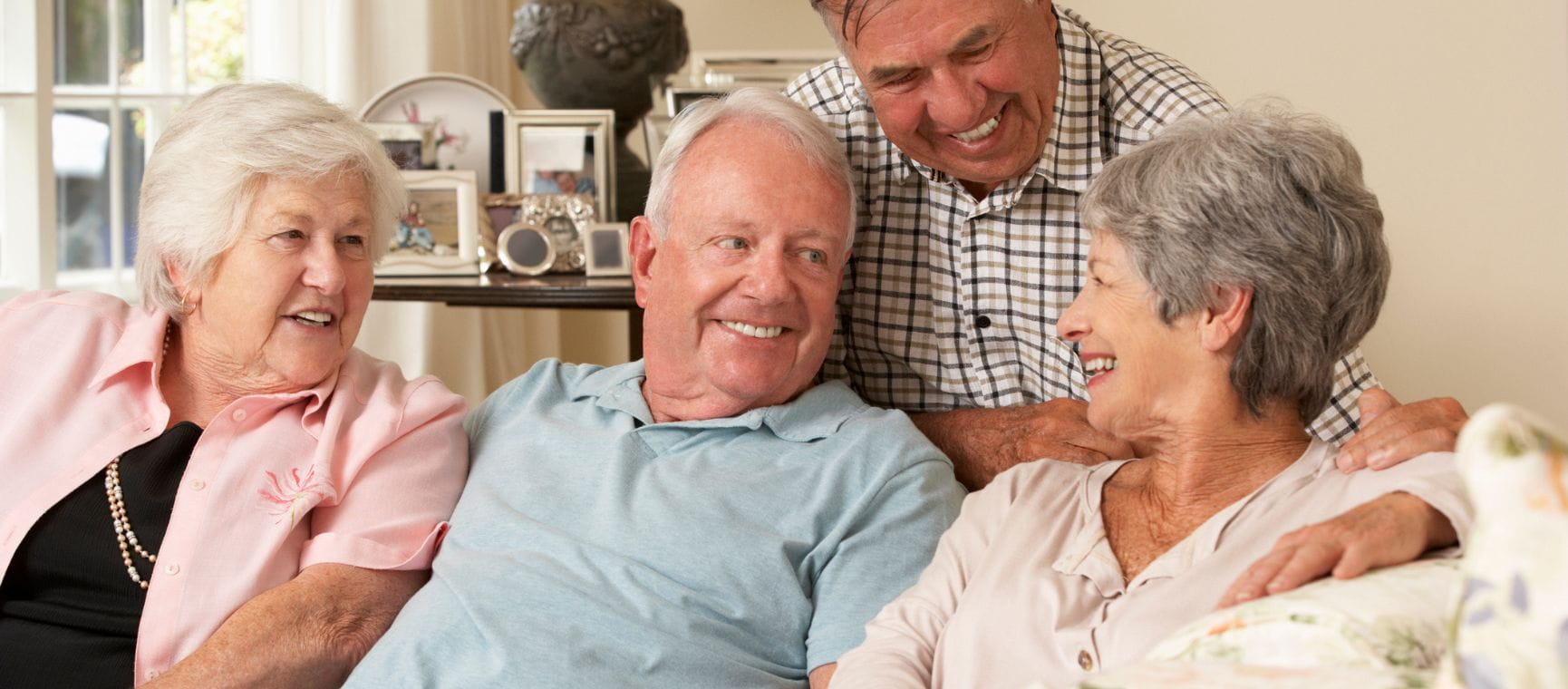 Two men and two women around a sofa all smiling and chatting