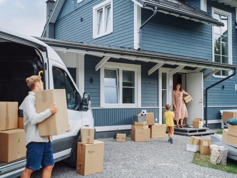 A family unloading a van as they move into a house