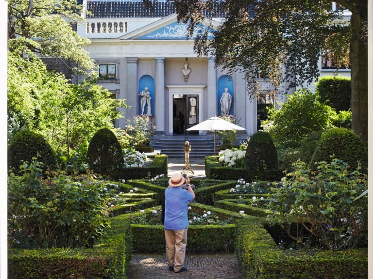 A man taking a photo in the gardens of the Museum Van Loon  in Amsterdam | Richard Taylor/4Corners