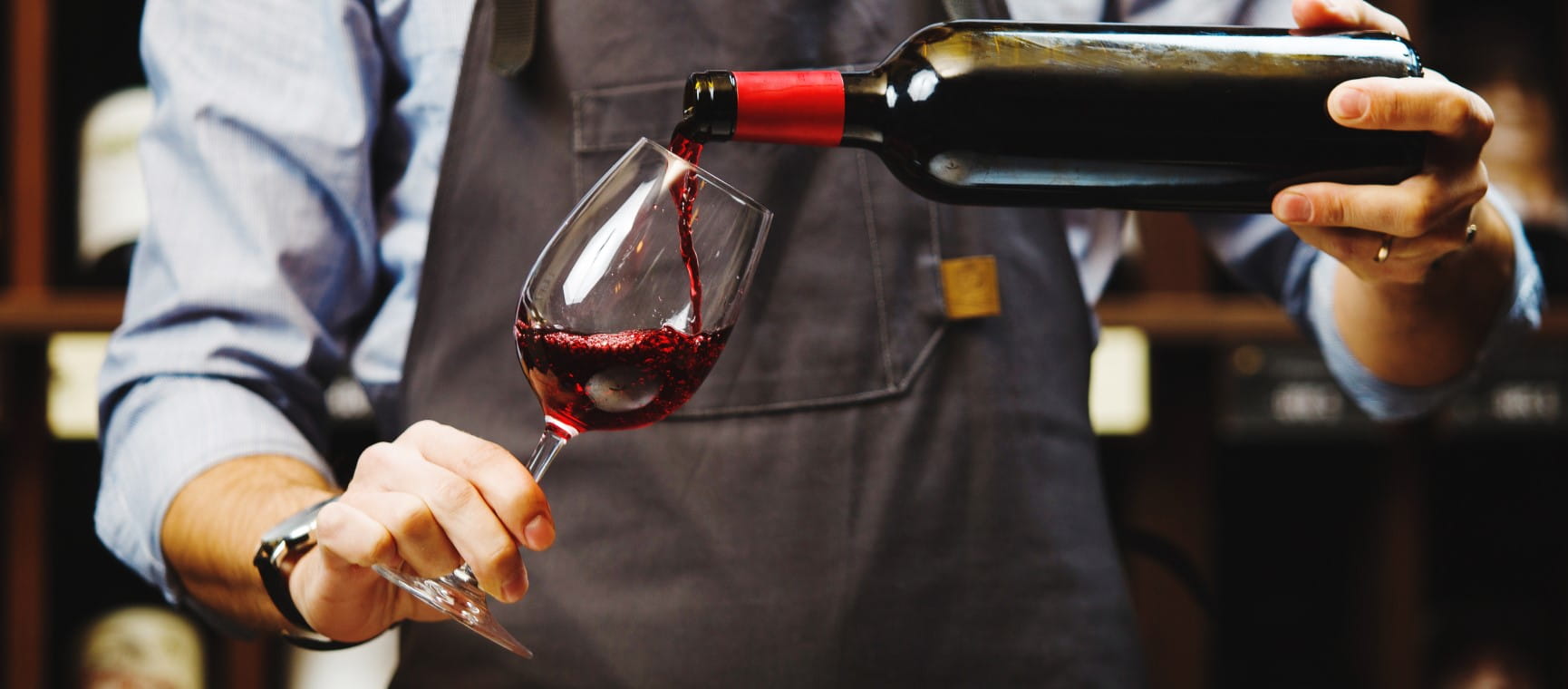 Sommelier pouring red wine into long-stemmed wineglass | Getty/IL21