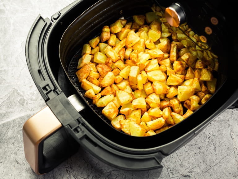 Chopped cooked potatoes in an air fryer drawer