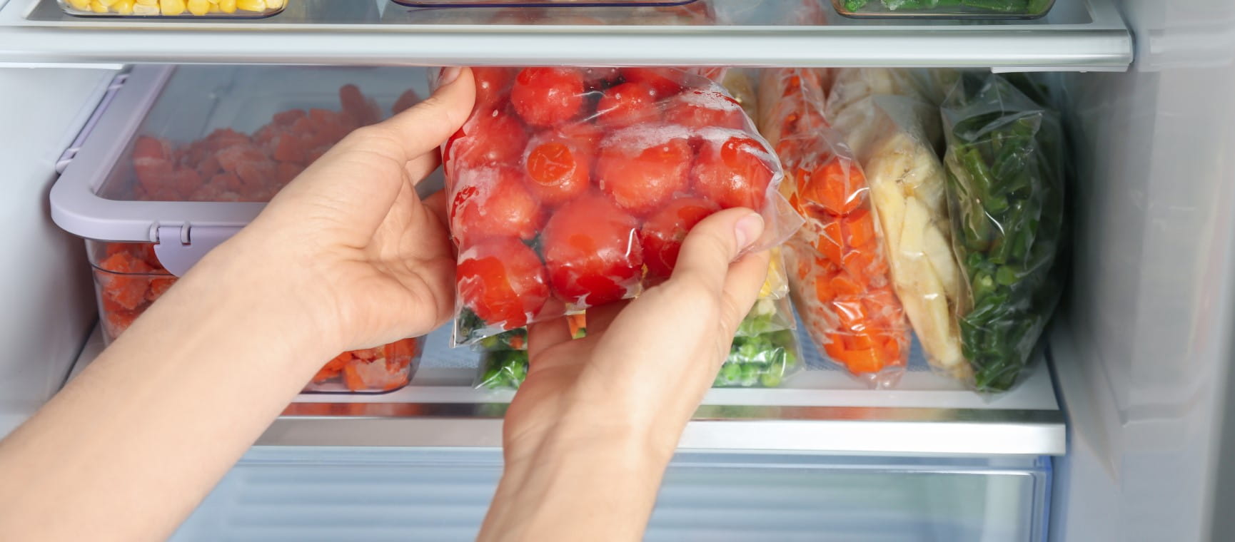 A person putting tomatoes away - but should tomatoes be stored in the fridge? | GettyLiudmila Chernetska