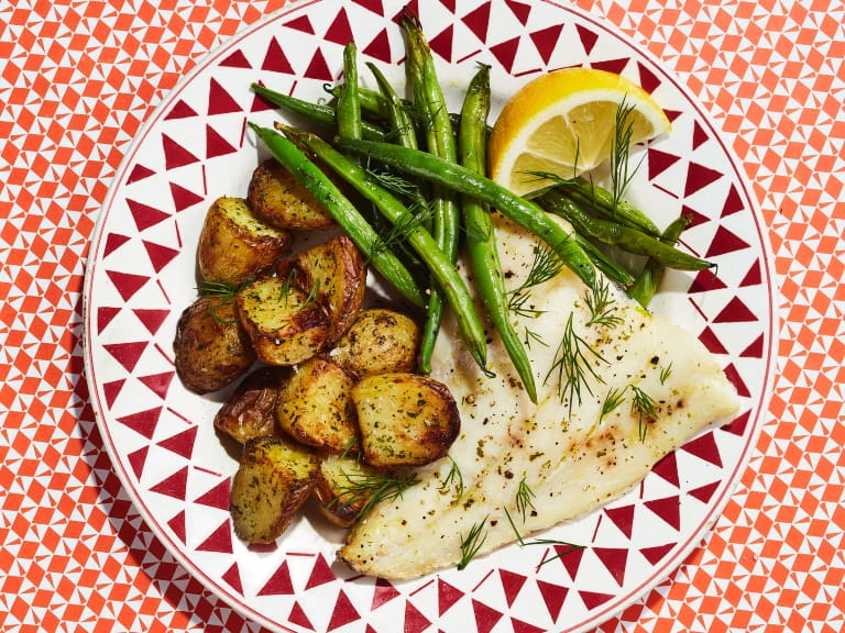 Air fryer smoked haddock, new potatoes and green beans served on a red and white plate 