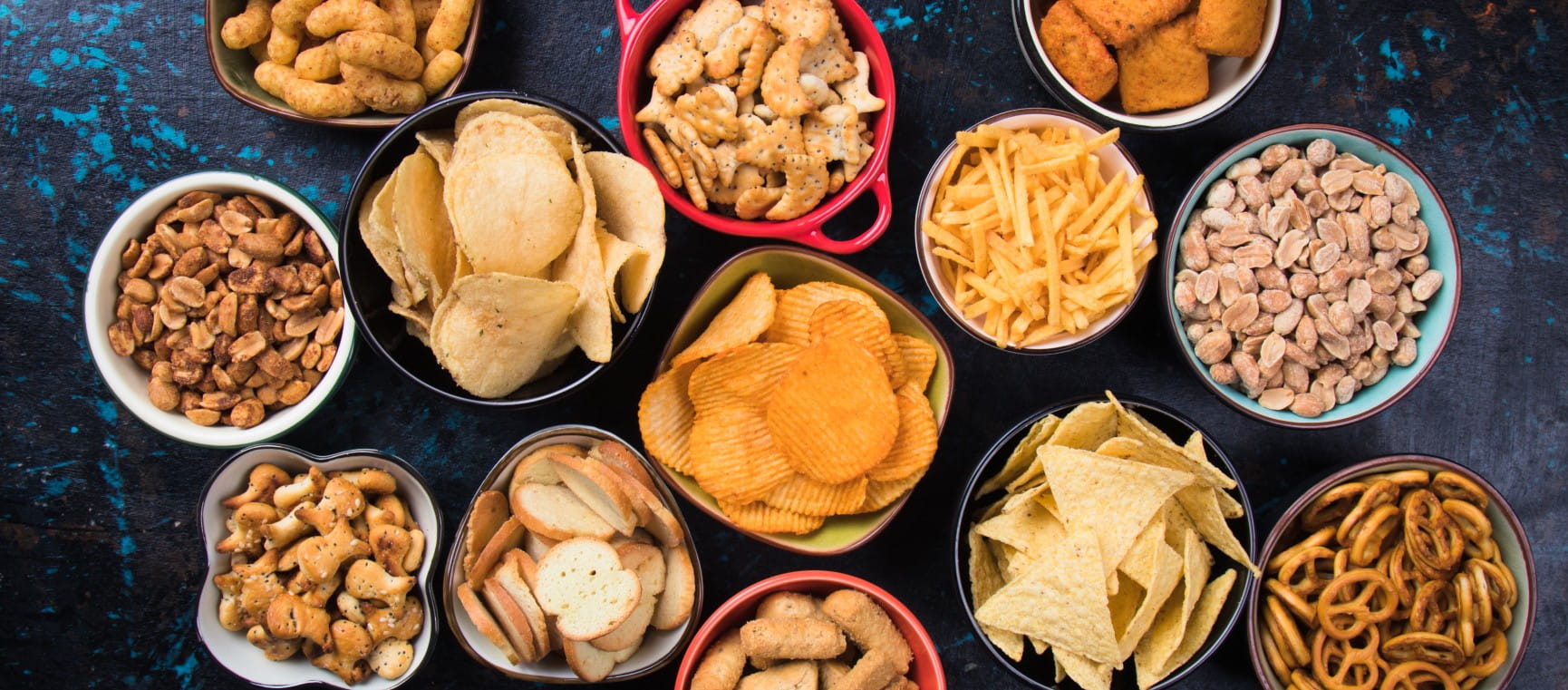 Salty snack including peanuts, potato chips and pretzels served as party food in bowls | Getty/IgorDutina