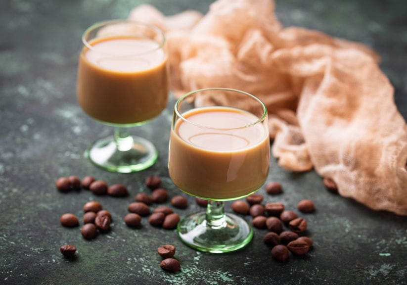 two glasses of baileys cream liqueur with coffee beans scattered around