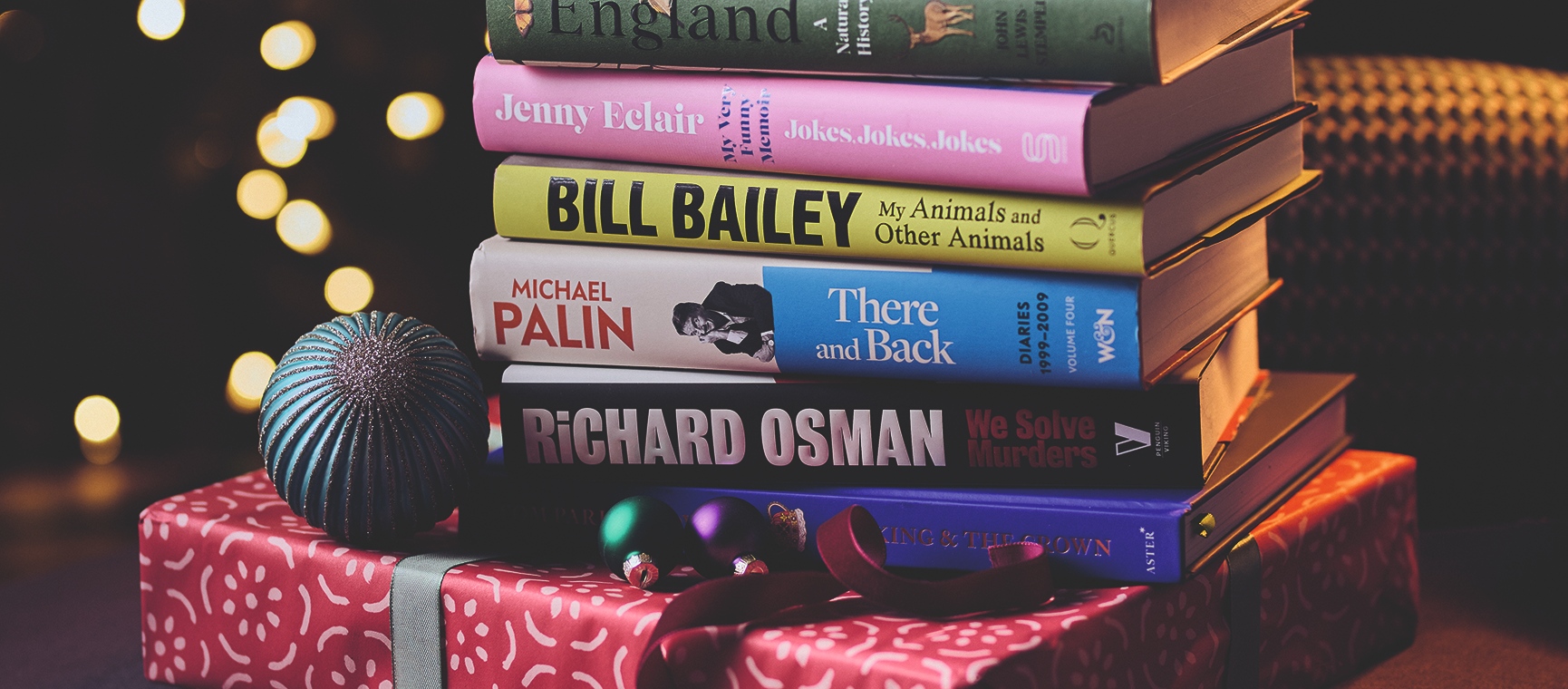 A stack of hardback books on top of a wrapped Christmas gift